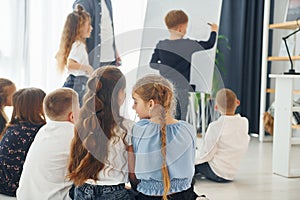 Boy writing on the board. Group of children students in class at school with teacher