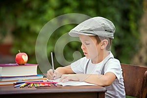 Boy, writing his homework from school, drawing and writing in hi
