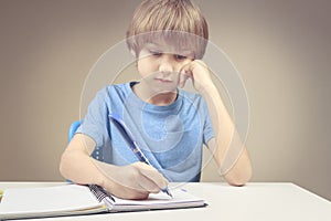 Boy writing on paper notebook. Boy doing his homework exercises