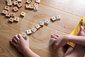 Boy writing  words stay home made of wooden blocks. Self quarantine at home or stay at home concept. Top view