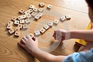 Boy writtng  words stay home made of wooden blocks. Self quarantine at home or stay at home concept. Top view