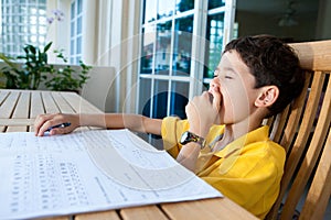 Boy yawning while doing his homework