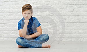 Boy 9-10 years old in a blue shirt on a light background, the emotion of resentment