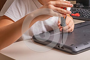 A boy of 10 years old is sorting a laptop for cleaning and maintenance. Selective focus. Screwdrivers, purge cylinder, magnifying photo