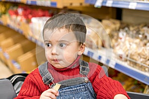 Boy 2 years in a store on the background of bread