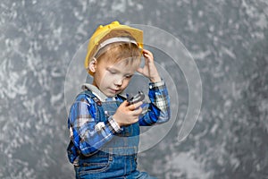 The boy in yellow hard hat holding a pipe wrench in the hands
