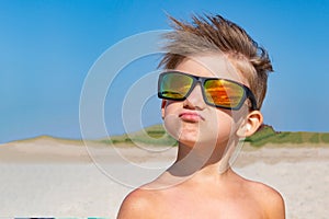 A boy in yellow sunglasses looks up, hair develops on his head.