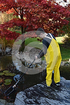 Boy working in the garden, cleaning the pond