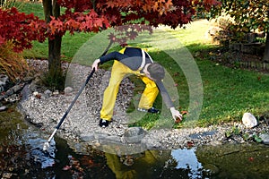 Boy working in the garden, cleaning the pond