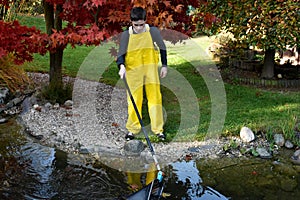 Boy working in the garden, cleaning the pond