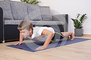 Boy on yoga mat at home holding plank pose. Child physical activity on quarantine Healhty lifestyle active leisure