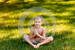 Boy Yogi sits on green grass