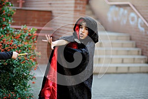 Boy of younger school age in a black-red cloak portrays the evil sorcerer