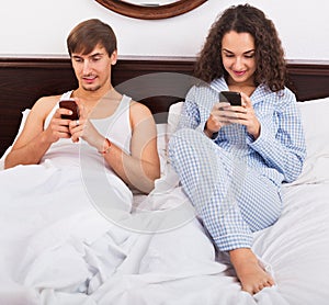 Boyfriend and beautiful girlfriend busy with smartphones