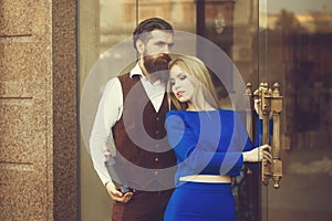 Boyfriend with bottle of wine hugging girlfriend at glass door