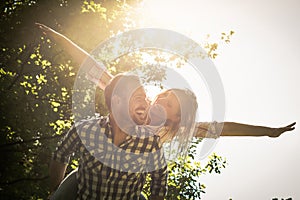 Boyfriend carries the girl on her back with open arms. Happy co