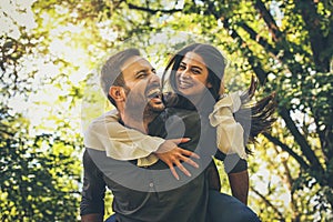 Boyfriend carrying his girlfriend on piggyback. Portrait.