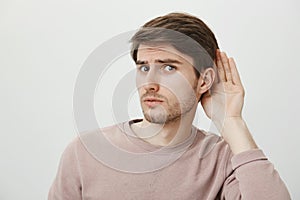 Boyfriend do not believe his couple and spying on her. Portrait of worried guy having trust issues, frowning and looking