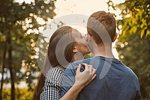 Girl kissing boy in cheek in the park, concept of teen love