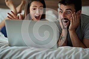 Boyfriend and girlfriend surfing the net in bed