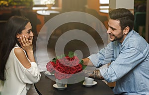 Boyfriend Giving Surprised Girlfriend Beautiful Bouquet Of Roses In Cafeteria