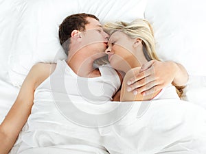 Boyfriend kissing her girlfriend in bed