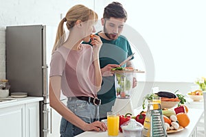 boyfriend preparing vegetable juice with juicer at kitchen