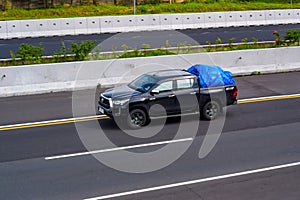 Black Toyota Hilux double cabin truck driving fast on trans jawa highway toll road