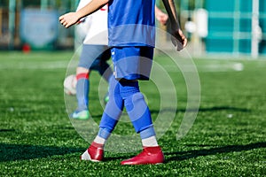Boys at blue white sportswear run, dribble, attack on football field. Young soccer players with ball on green grass. Training
