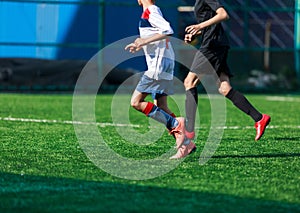 Boys at blue white sportswear run, dribble, attack on football field. Young soccer players with ball on green grass. Training