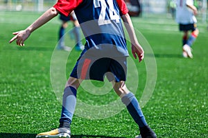 Boys at blue white sportswear run, dribble, attack on football field. Young soccer players with ball on green grass. Training