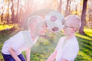 Boys brothers playing with ball on green grass in park.