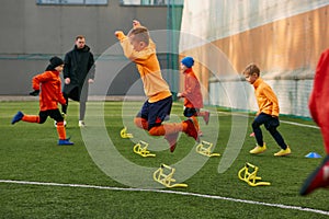 Boys, children, football players doing exercises, warming up before training session with coach on sports field outdoors