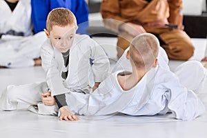 Boys, children in white kimono training judo, jiu-jitsu fight style indoors. Developing strength, attention and