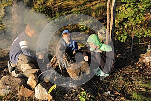 Boys by fire in forest in evening