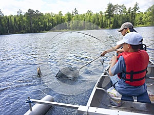 Boys fishing in a canoe catch a walleye