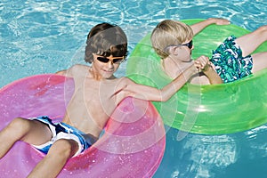 Boys On Float Tubes In Swimming Pool