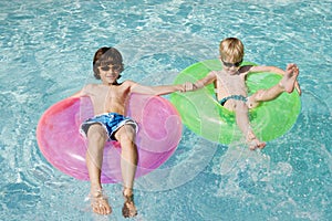 Boys On Float Tubes In Swimming Pool