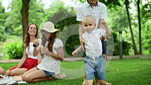 Boys and girl playing in forest. Laughing parents relaxing with children in park