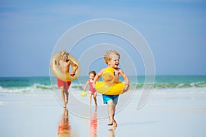 Boys and girl run with inflatable buoys doughnut, duck at beach