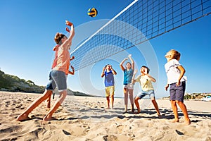 Boys and girls playing volleyball on the beach