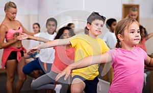 Boys and girls training along ballet bar