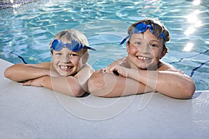 Boys grinning on side of swimming pool