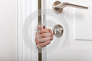 Boys hand sticking out of closed door. Prevent child hazard concept. School kid playing hide and seek game at home or at