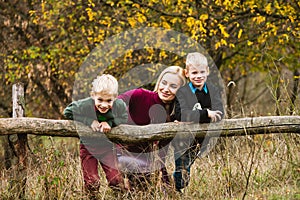 Boys hang on wooden log with mother