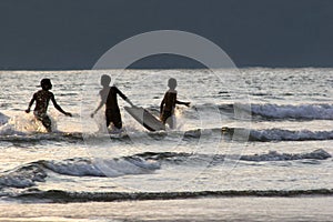 Los chicos divirtiéndose surfear sobre el atardecer 