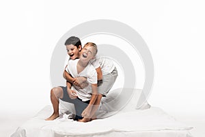 Boys imitating fighting while having fun on bed isolated on white