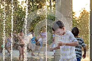 Boys jumping in water fountains. Children playing with a city fo