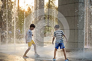 Boys jumping in water fountains. Children playing with a city fo