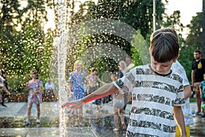 Boys jumping in water fountains. Children playing with a city fountain on hot summer day. Happy friends having fun in fountain.